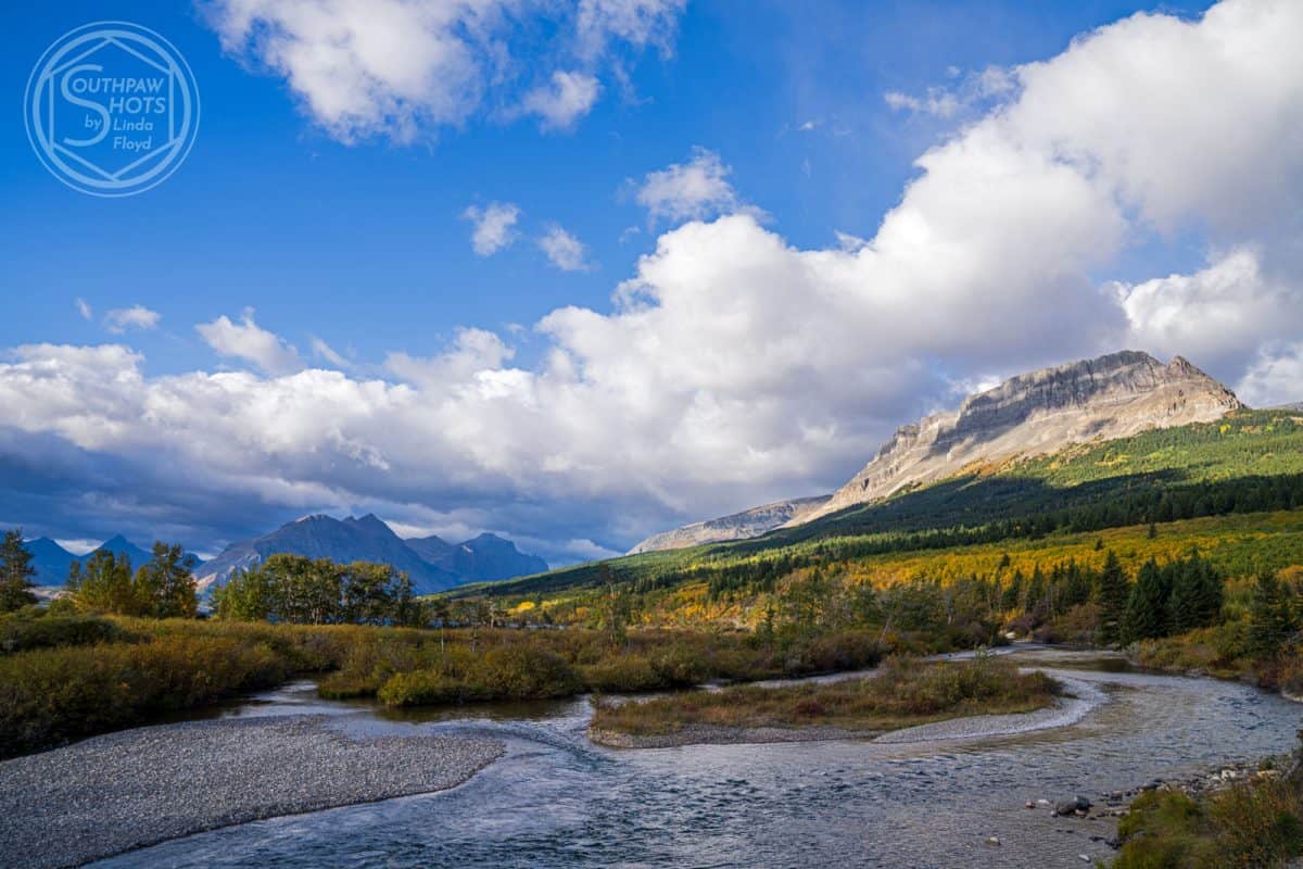 a river running through a valley with mountains in the background